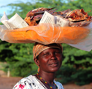 A Kenyan woman carries a basket of crabs on her head.