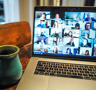 Laptop open to a Zoom call with a coffee cup